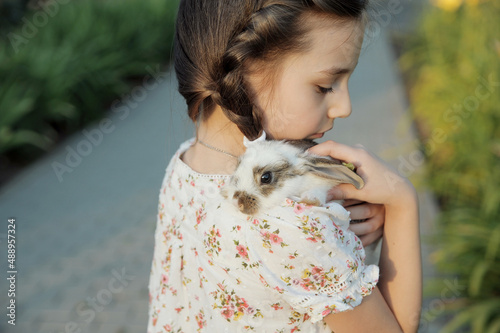Girl hugging baby rabbit outdoors
