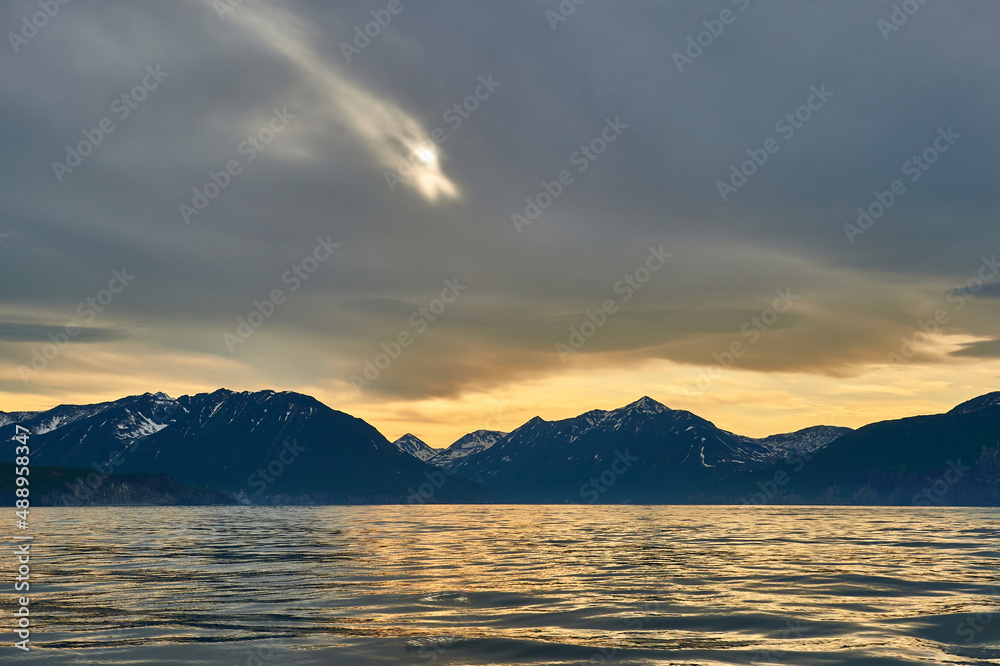 Sea sunset on the background of volcanoes and mountains. Kamchatka, Russia. Sea cruises and travel