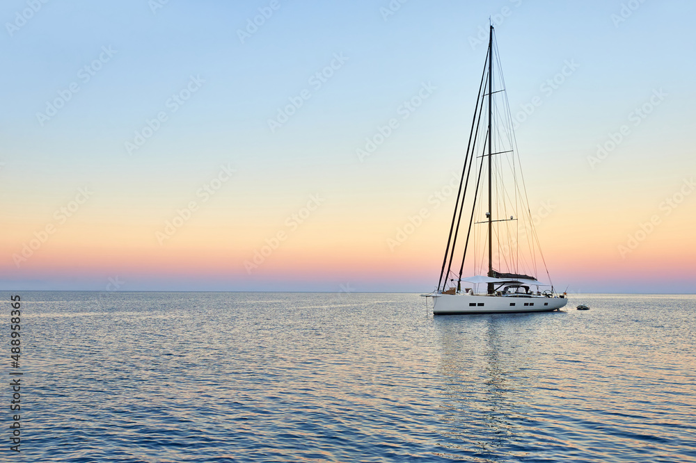 Fototapeta premium Sailing yacht at sunset in the sea. Travel and yachting