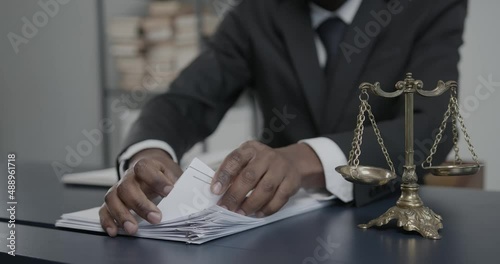 African american lawyer working on a lawsuit or complaint and going through paperwork, faceless photo
