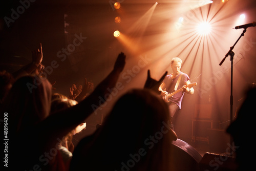 Rear view of an excited crowd cheering their favourite band on beneath the strobe lights at a festival. This concert was created for the sole purpose of this photo shoot, featuring 300 models and 3