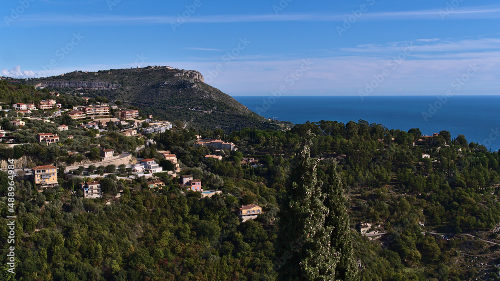 Beautiful view over the wood-covered hills of the mediterranean coast near small village Eze at the French Riviera with residential buildings.
