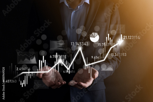 Obraz na płótnie Businessman in hand hold banking business finance graph and invest in stock market investment point,economic growth and investor concept