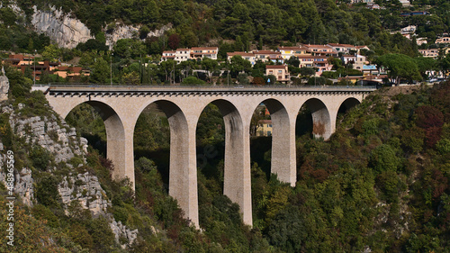View of a beige colored road bridge with arches near small village Eze located on the hills above the mediterranean coast in southern France in autumn.