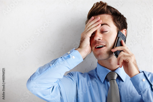 Utter relief after getting the promotion. A relieved young businessman rubbing his face while taking a call. photo