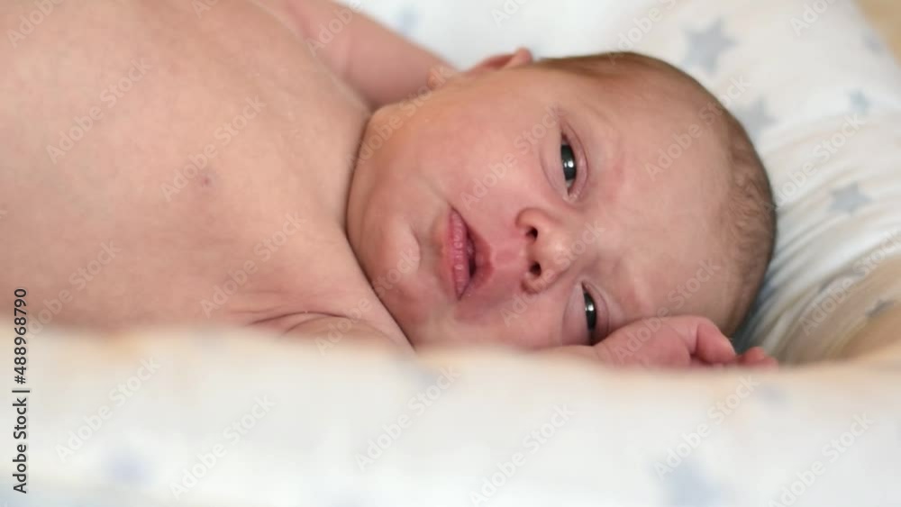 Closeup portrait of Newborn baby on white blanket. Soft focus. Infant is lying, yawning. One, two week age. Infant girl waking up on bed at home. New life and growing up concept. Real People. Closeup portrait of Newborn baby on white blanket. Soft focus. Infant is lying, yawning. One, two week age. Infant girl waking up on bed at home. New life and growing up concept. Real People.