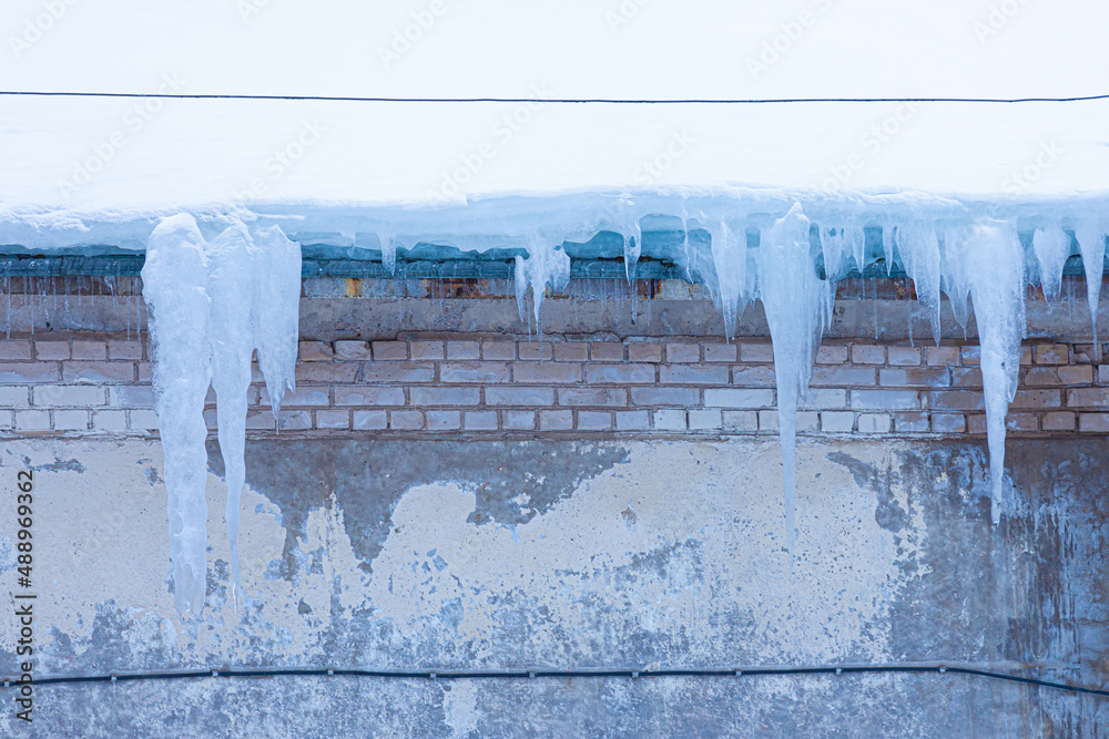 Bright, vivid and colorful background of icicles hanging from the rim of the roof. The spring or winter background of melting ice and snow in the sunny day Bright, vivid and colorful background of icicles hanging from the rim of the roof. The spring or winter background of melting ice and snow in the sunny day