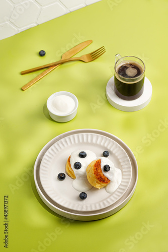 Still life in sunny day, breakfast idea on green background. Dessert on plate, Gold tableware