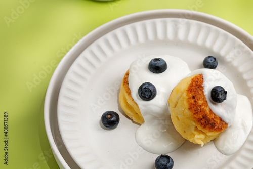 Close up dessert idea. Scheese pancake syrnik with cream and blueberry on white plate photo