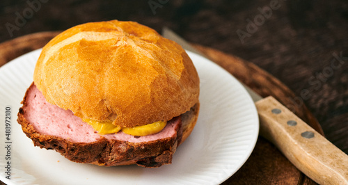 Frischer aufgebackener Leberkäse Fleischkäse in einer Semmel mit Ketchup Senf geschnitten zum mitnehmen