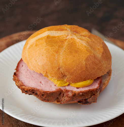 Frischer aufgebackener Leberkäse Fleischkäse in einer Semmel mit Ketchup Senf geschnitten zum mitnehmen