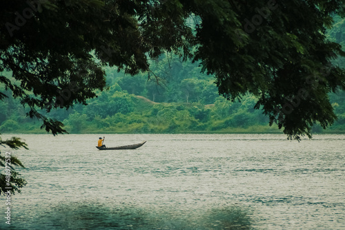 a boat is crossing a river that flows near the hilly forest photo