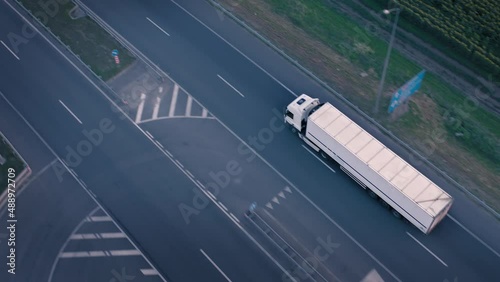 Moving white truck with semi-trailer on country road: transportation of commercial goods, transportation by truck: overhead drone tracking shot. White Shipping Truck moves to Logistic Warehouse center