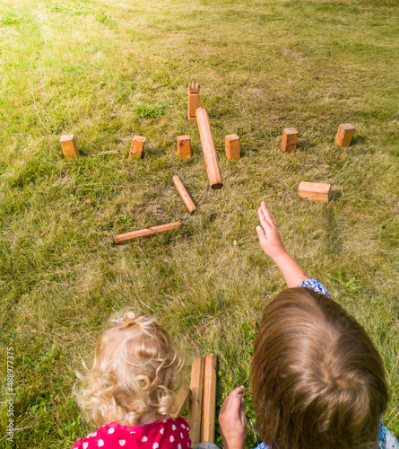 Kinder spielen Wikingerschach (Kubb) im Garten. Children play viking chess (kubb) in the garden.