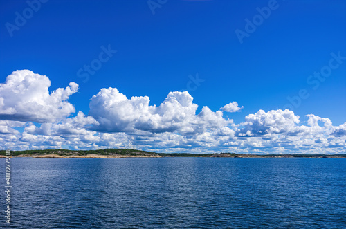 Skerries and coastline under a bright cloudy blue sky in the Koster fjord between the Koster islands and Strömstad, Bohuslän, Västra Götalands län, Sweden.