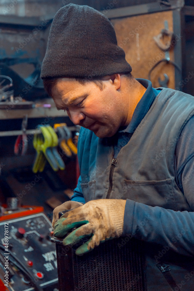 Welder cleans a copper car radiator with a metal brush