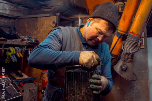 Welder cleans a copper car radiator with a metal brush