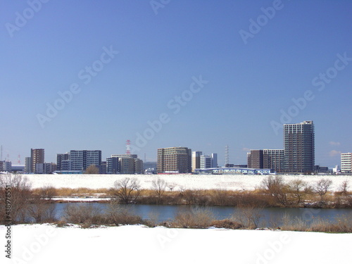 土手から見る早春の雪の残る江戸川河川敷風景