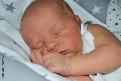 portrait of a sleeping newborn baby with his hands under his head.