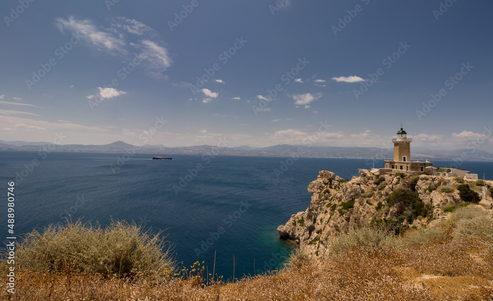 Lighthouse on the rocky hill, on the background of beautiful seascape of blue and turquoise Meditterranean Sea, mountains and floating ship Lighthouse on the rocky hill, on the background of beautiful seascape of blue and turquoise Meditterranean Sea, mountains and floating ship