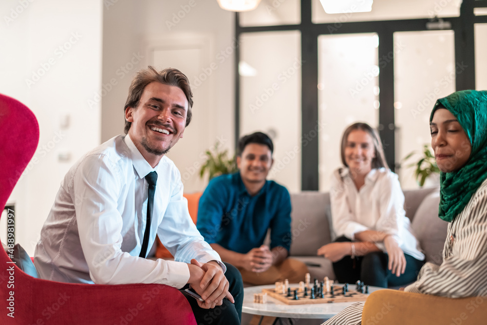 Fototapeta premium Multiethnic group of business people playing chess while having a break in relaxation area at modern startup office.