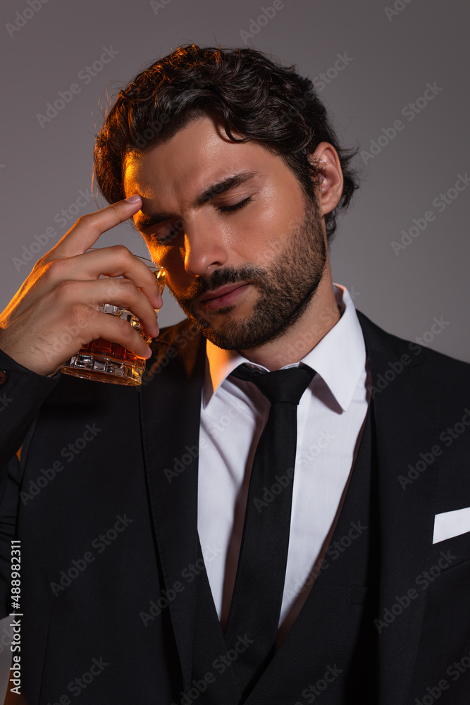 tired businessman with closed eyes holding glass of whiskey isolated on grey tired businessman with closed eyes holding glass of whiskey isolated on grey