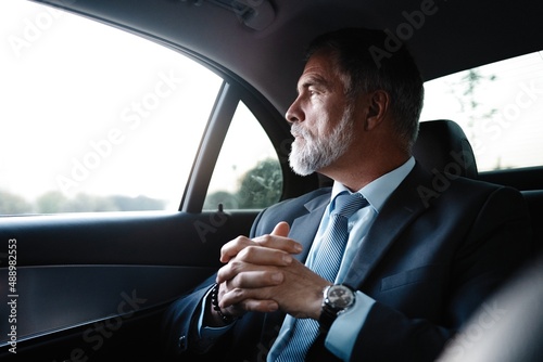 Mature handsome businessman is sitting in luxury car. Serious bearded man in suit. © opolja