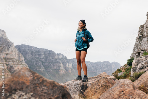 Smiling woman hiker enjoying the view. Young fit female in sports clothes enjoying the scenery during a mountain hike.