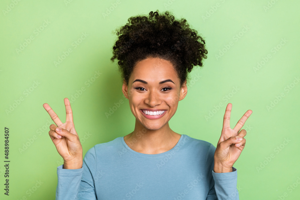 Photo of funny pretty lady dressed blue shirt showing tow v-signs isolated green color background Photo of funny pretty lady dressed blue shirt showing tow v-signs isolated green color background