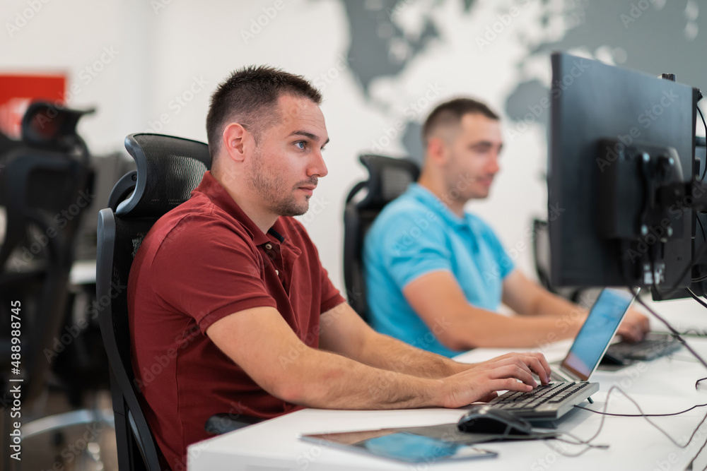 Group of Casual business man working on desktop computer in modern open plan startup office interior. Selective focus 