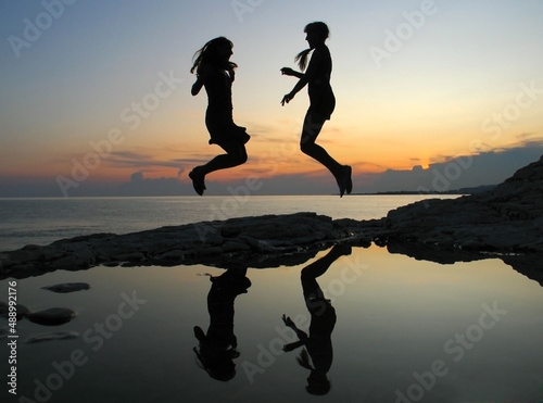 Female silhouettes on seacoast against the sunset sky