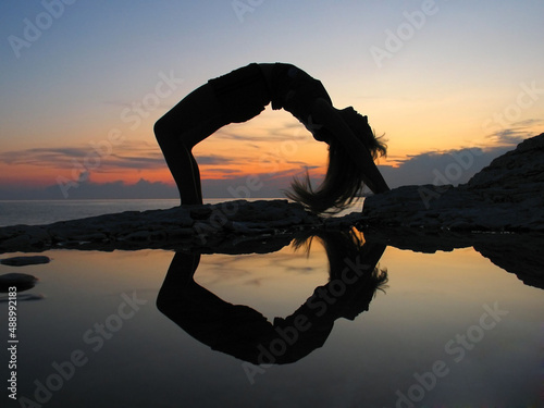 Female silhouette on seacoast against the sunset sky