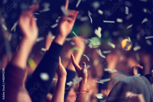 Wild and free. A music festival audience throwing confetti into the air in celebration.
