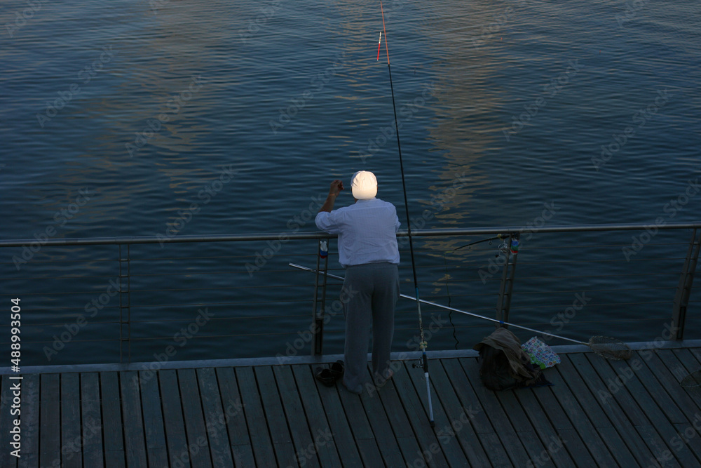 Kazan, Russia - July 22 2021 - fisherman standing on the shore of lake with fishing rod