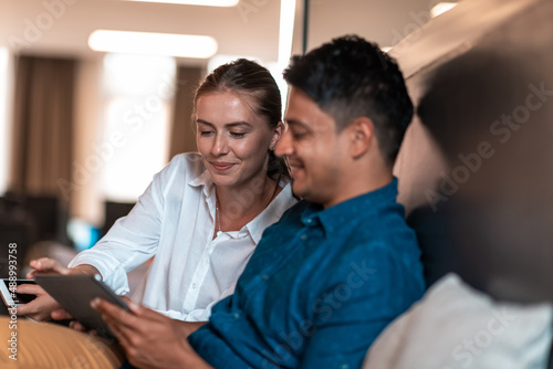 Multiethnic business people man with a female colleague working together on tablet computer in relaxation area of modern startup office