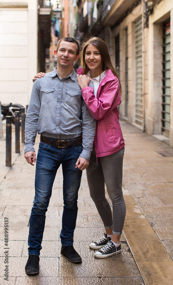 young couple guy and girl hugging walking along streets of european city