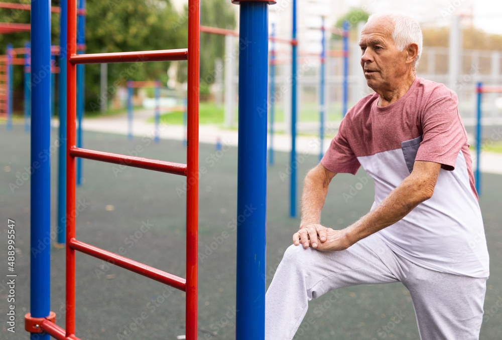 Elderly man doing gymnastic exercises in park Elderly man doing gymnastic exercises in park