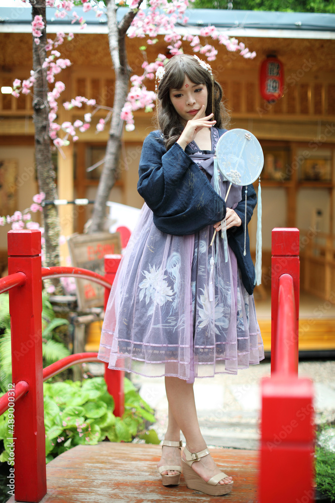 Naklejka premium Beautiful young woman with dark blue Chinese lolita dress with Chinese garden