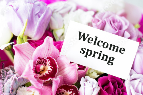 Welcome Spring text on a card against a background of spring flowers