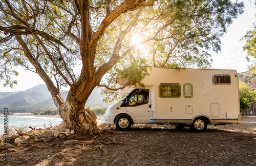 Fotografering Motorhome RV parked on the beach under a tree facing the sea, Crete, Greece