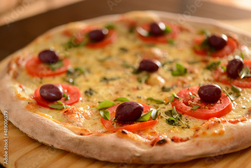 Pizza Margherita with olives close-up on wooden shovel.