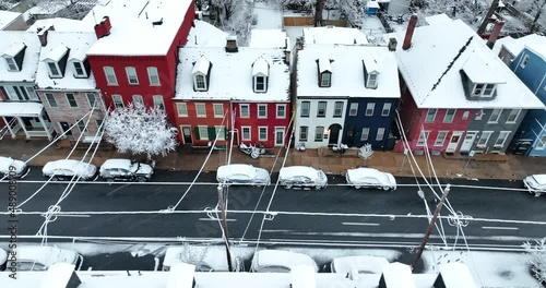 Colorful row homes in urban city in USA during winter snowstorm. Snowflakes falling at night. Aerial truck shot. Establishing scene. photo