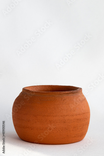 A vertical photograph of a clay pot on a white background. copy space © K64End