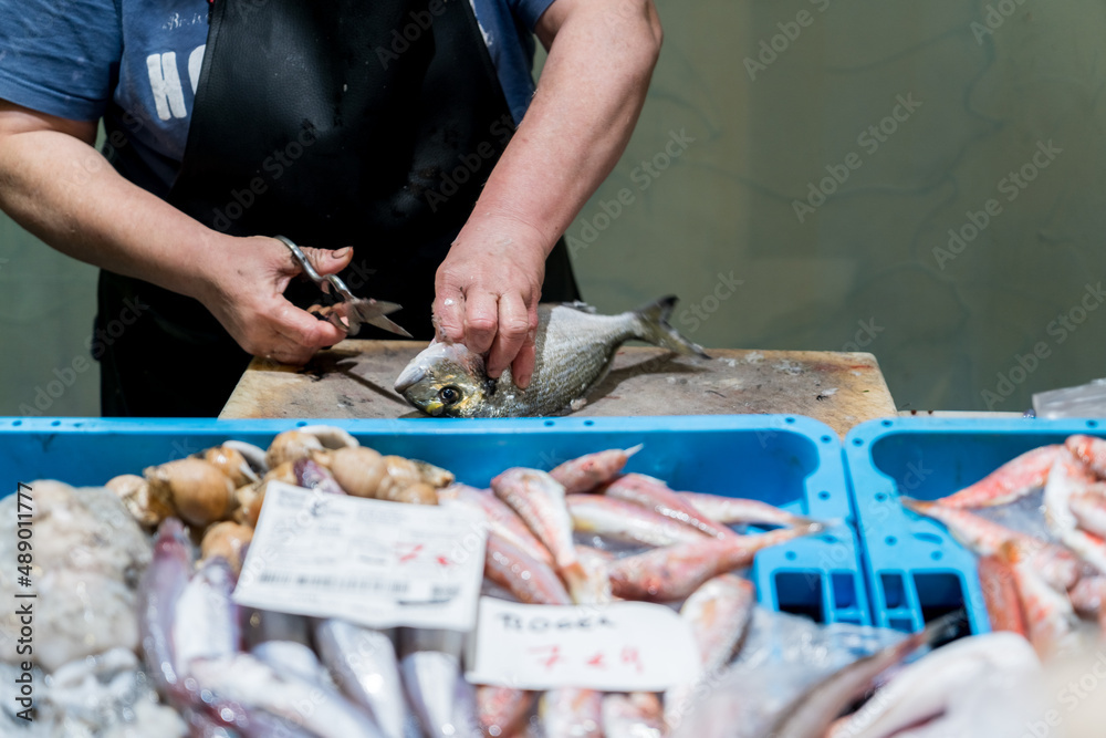 Fishmonger hands cleaning fish in her fish shop. 