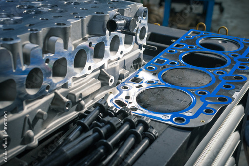 New cylinder head with gasket and bolts on a table in a car repair shop. Blur effect.