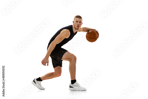 Young muscled man, basketball player practicing with ball isolated on white studio background. Sport, motion, activity concepts. © master1305