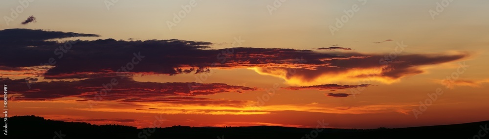 Sunset panorama. Dramatically fiery sky with clouds. Beautiful landscape.