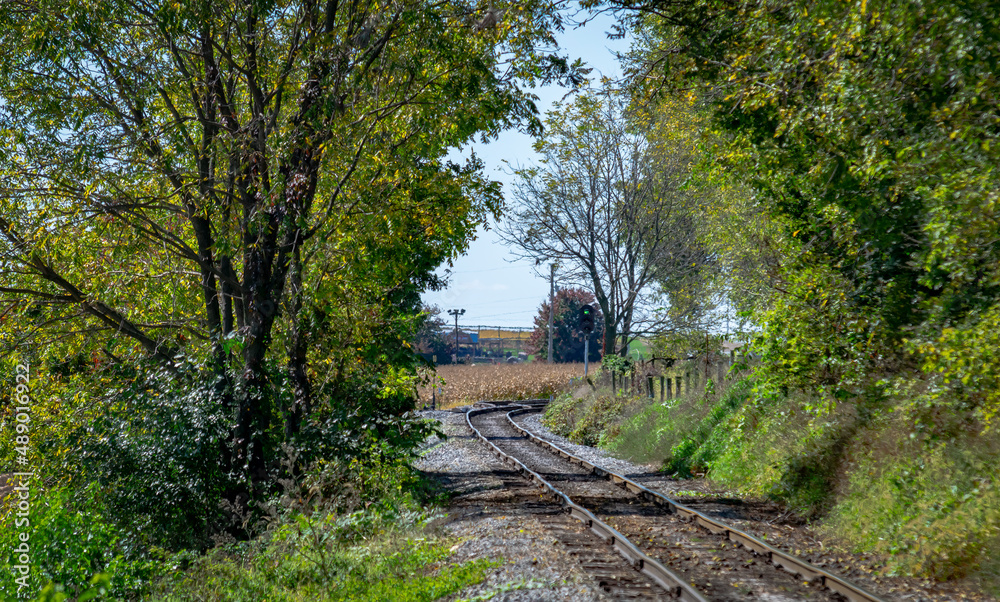 A Lonely Rail Road Track Going Around a Bend Thru Trees and Farmland on a Sunny Day A Lonely Rail Road Track Going Around a Bend Thru Trees and Farmland on a Sunny Day