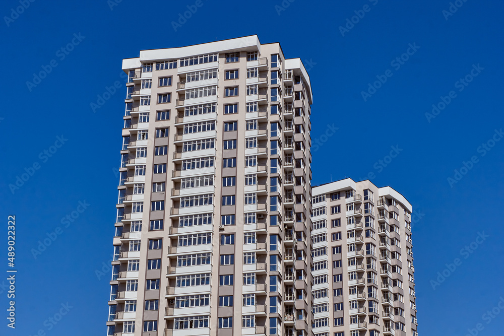 Modern new residential concrete high-rises on a background of the sky. Front view part of multi-storey new built. Modern multi-storey residential area. Residential fund.