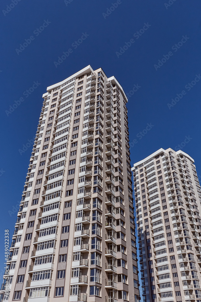 Modern new residential concrete high-rises on a background of the sky. Front view part of multi-storey new built. Modern multi-storey residential area. Residential fund.